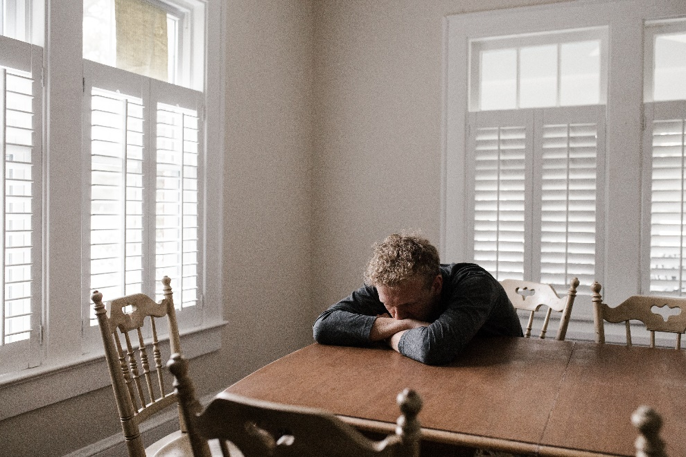 Distressed man with his head down on a wooden table
