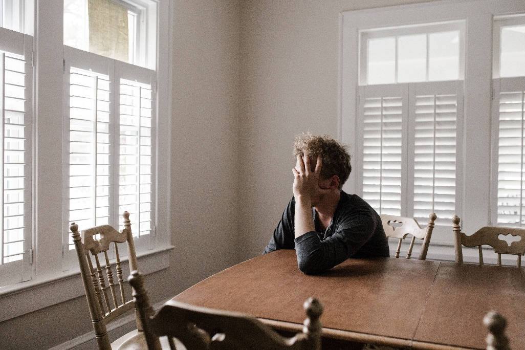 A stressed man leaning on a wooden table
