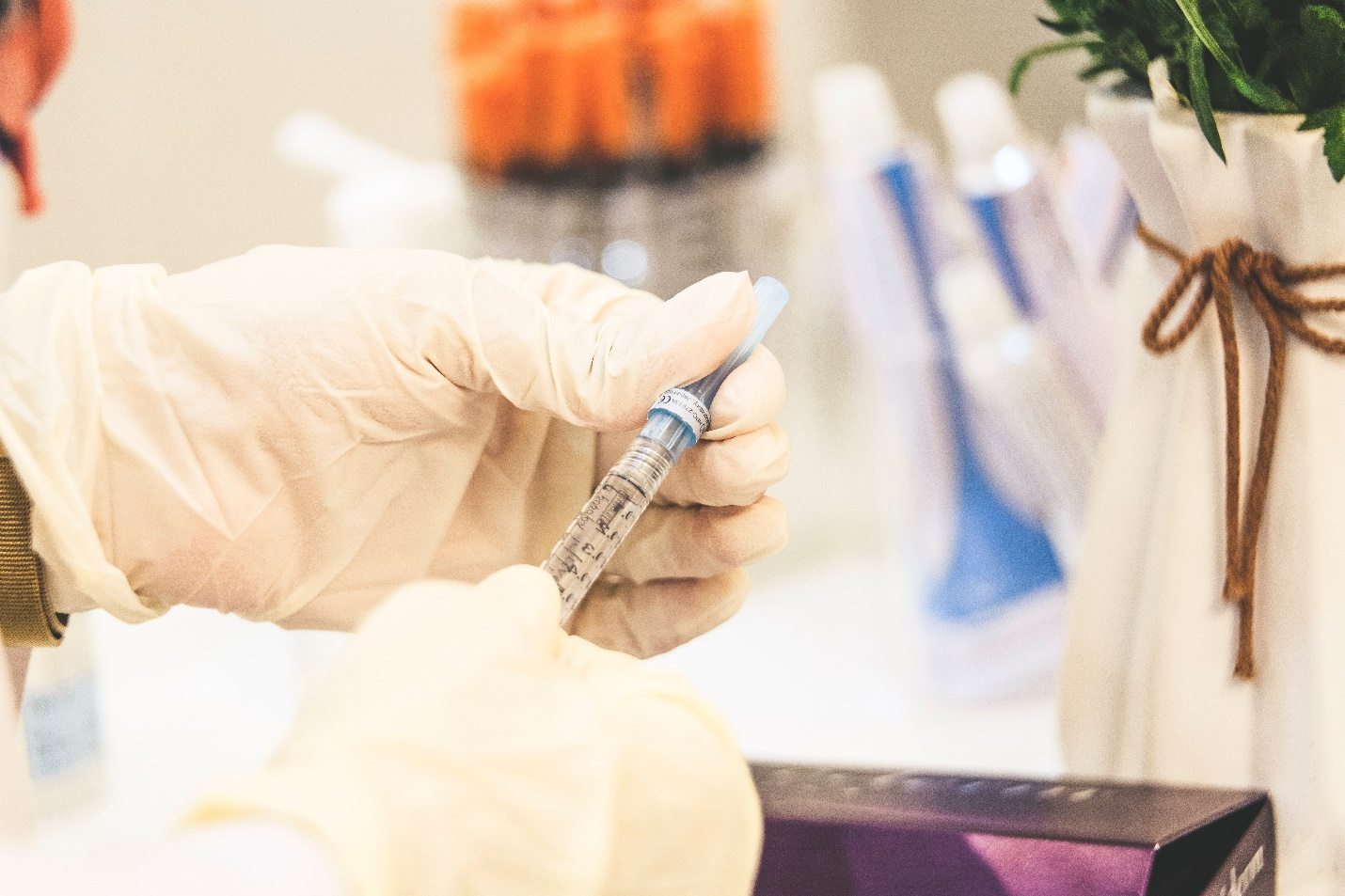 a pair of gloved hands holding a syringe
