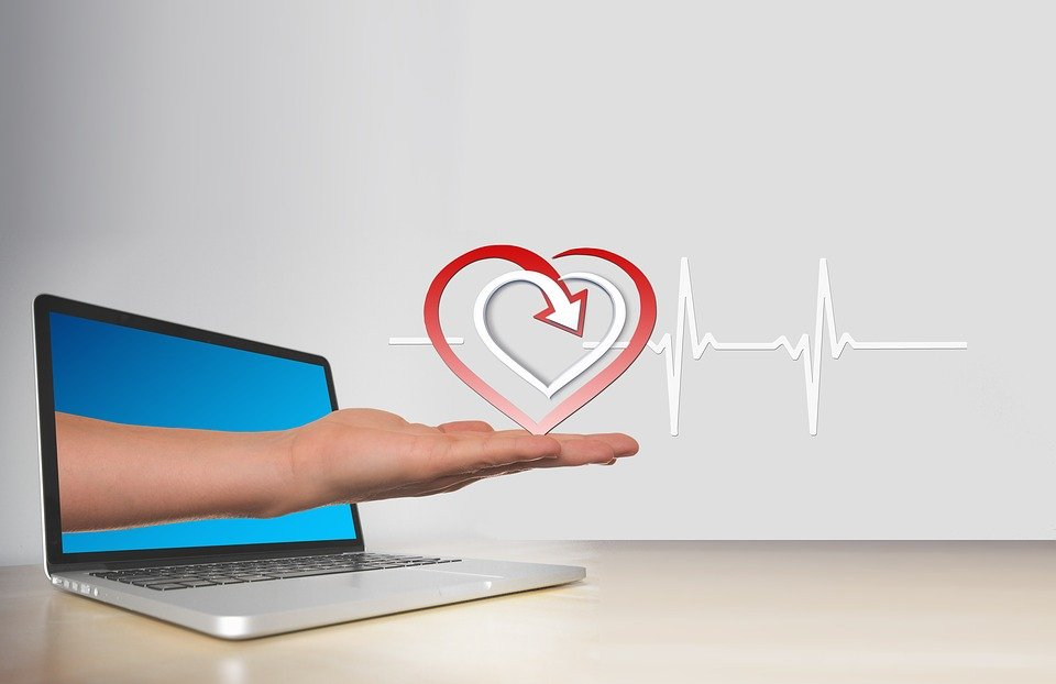 A hand coming out of a laptop holding a heart symbol