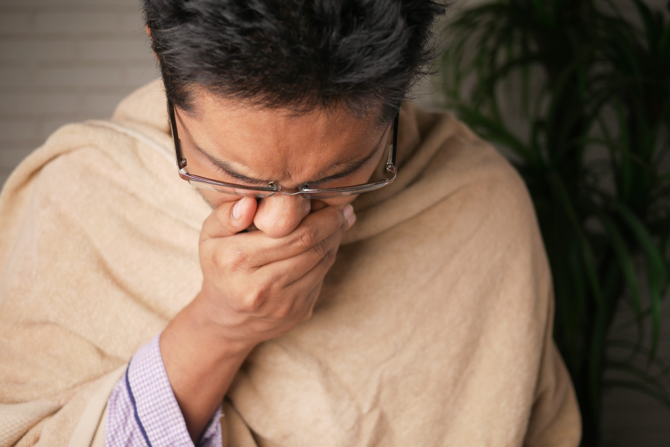 A man coughing with his hand over his mouth