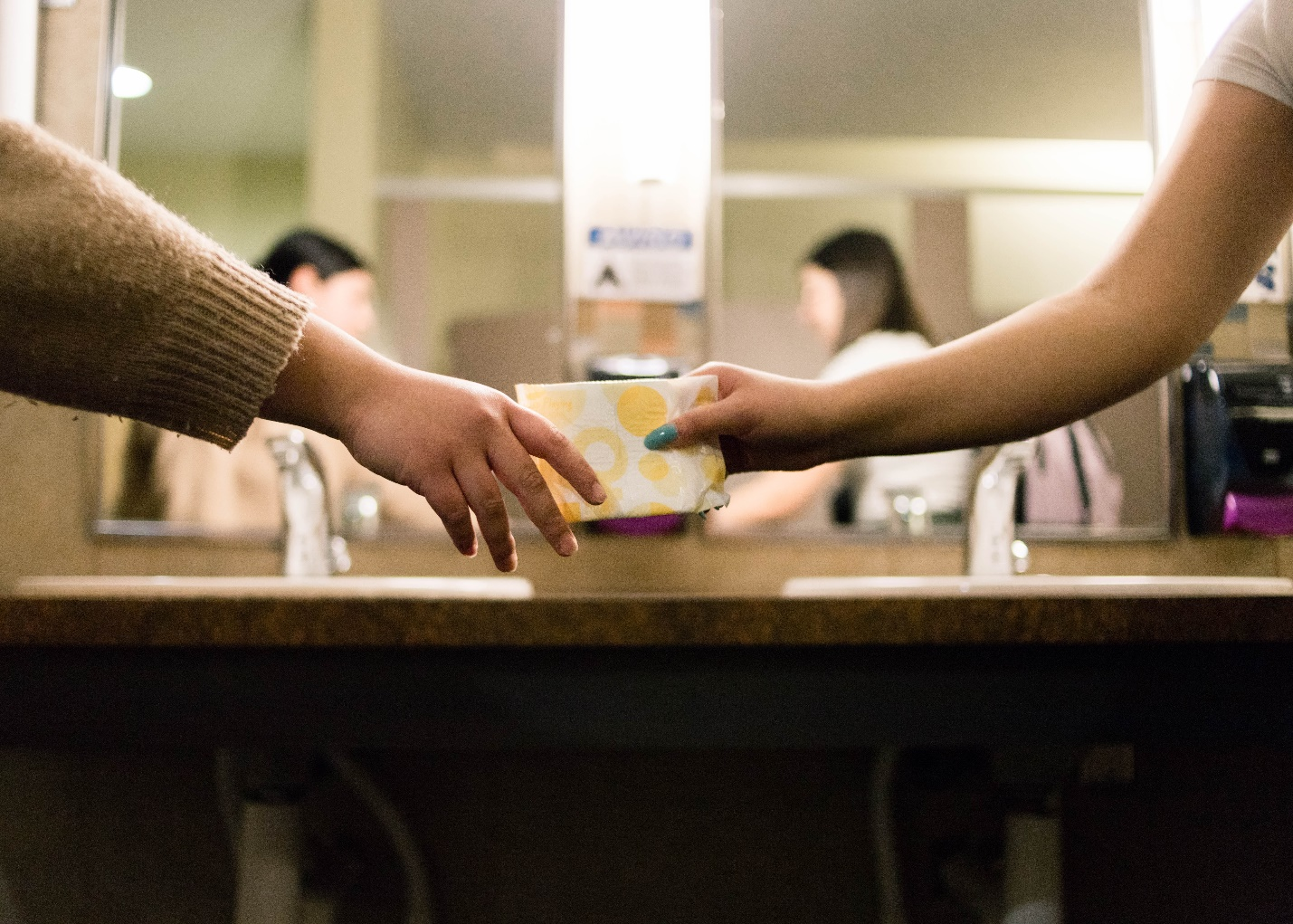 A sanitary napkin passing from one hand to another