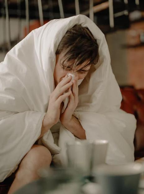 Man wiping nose with tissue. 