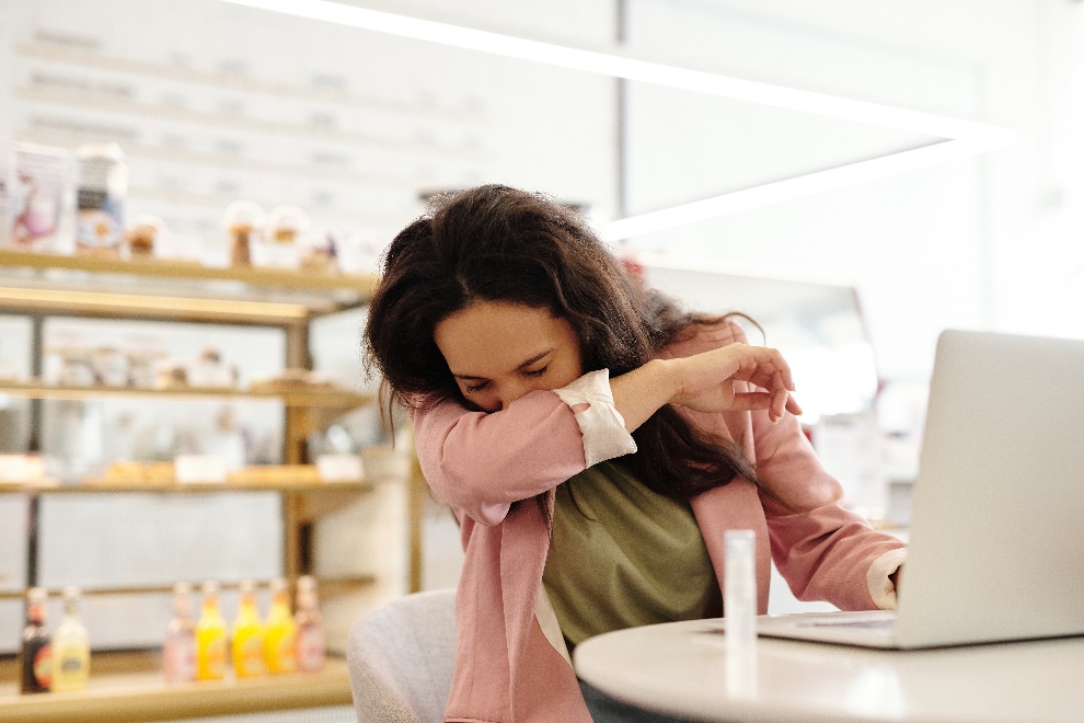  a sick woman covering her mouth while sneezing