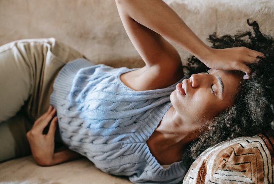 Woman lying on a couch, feeling unwell. 