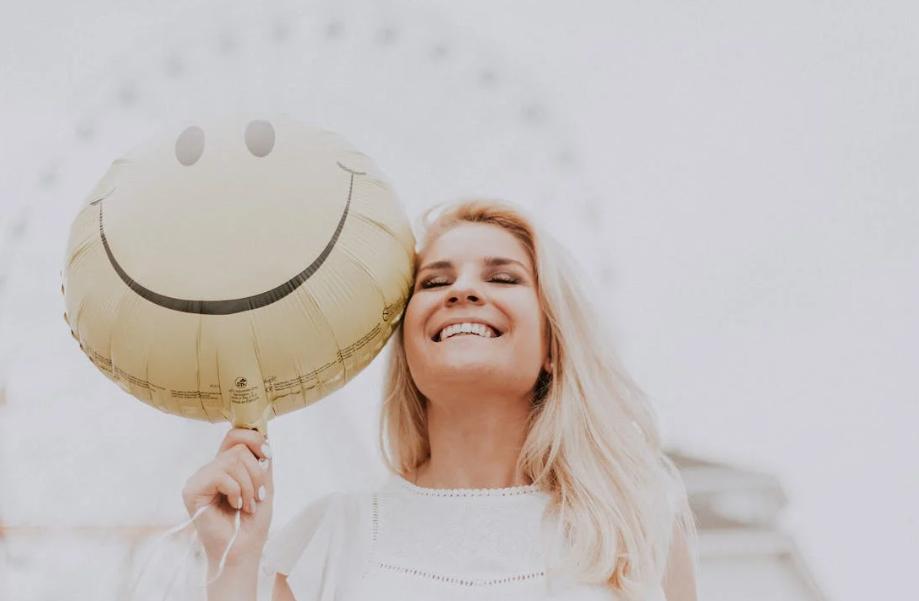 Woman holding a smiley balloon.