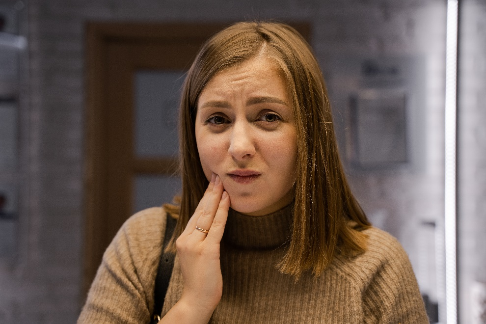 A woman wearing a turtle neck with her hand on her cheek