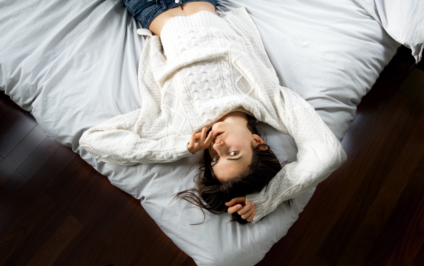 An upside-down shot of a woman wearing a white sweater 
