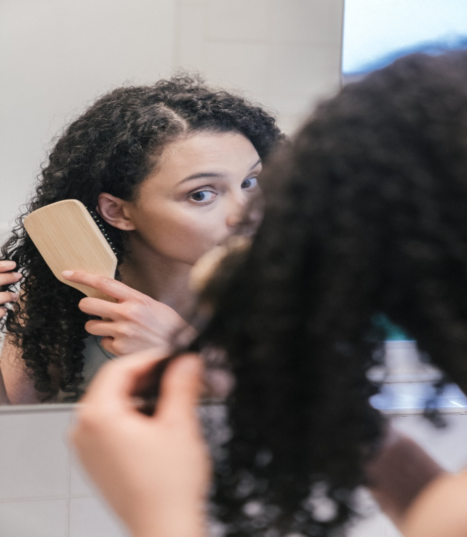 Woman suffering from hair loss while brushing her hair. 