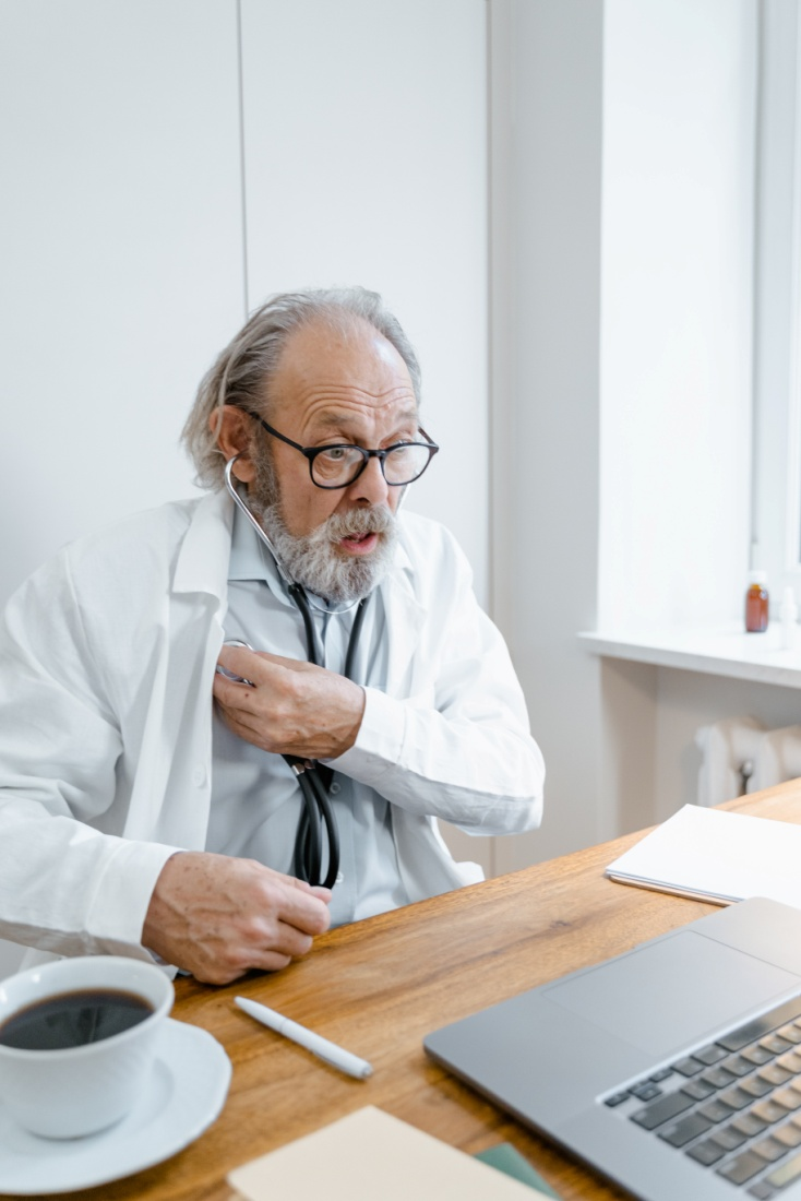 An online doctor using a stethoscope during a virtual consultation