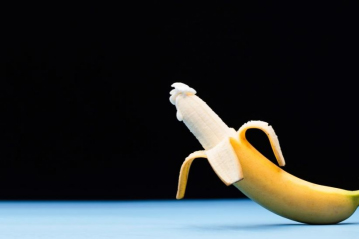 A half peeled banana with cream on the tip