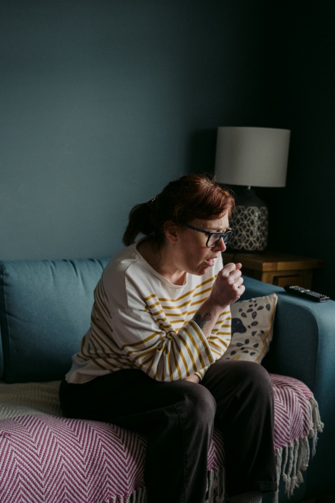  A woman sitting on a sofa, coughing