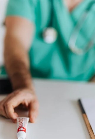 A medical physician placing an ointment on a white table