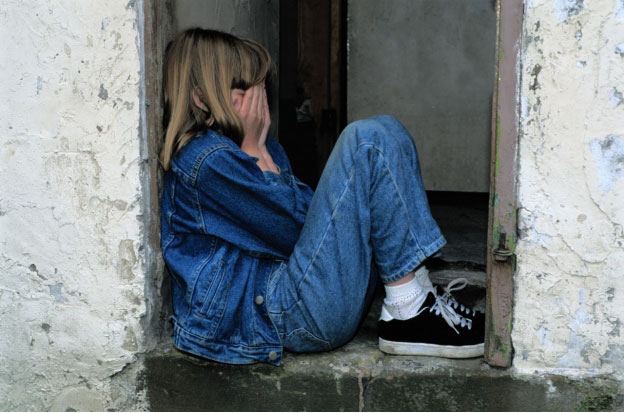 a girl sitting with her hands covering her face