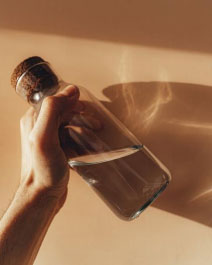 a person holding a glass water bottle 