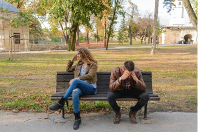 A woman and man sitting on a brown bench