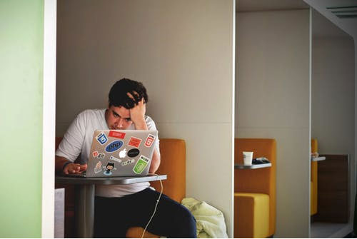 a stressed out person holding his head while working on a laptop