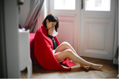 Sick woman wiping her nose sitting on the floor