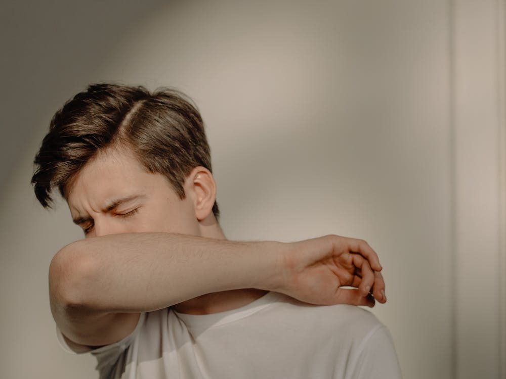 A man covering his mouth while sneezing
