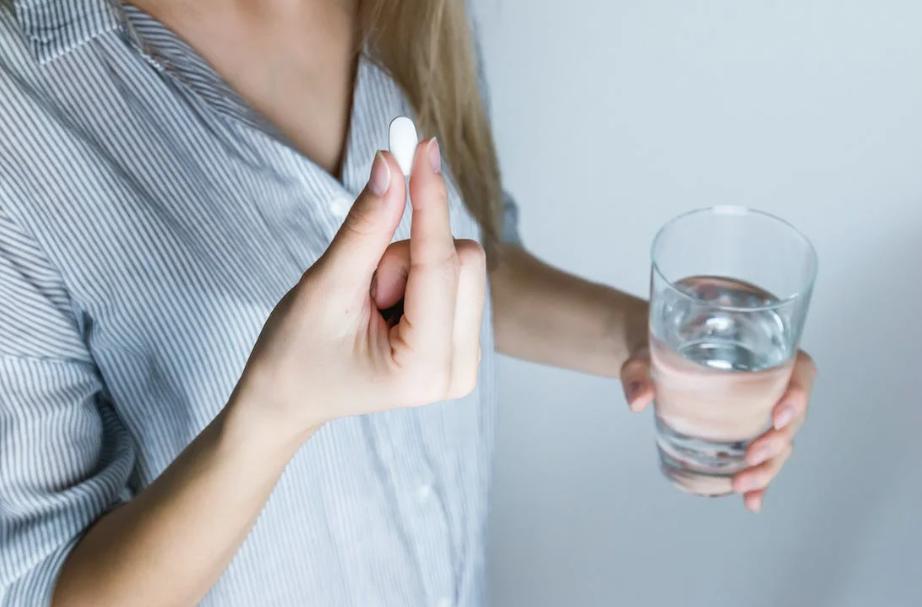 Woman taking a white pill. 