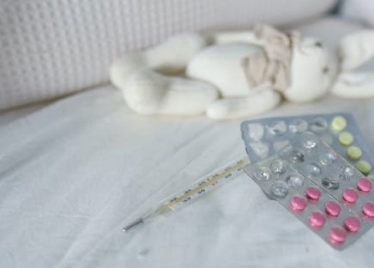 Thermometer and pills on bed