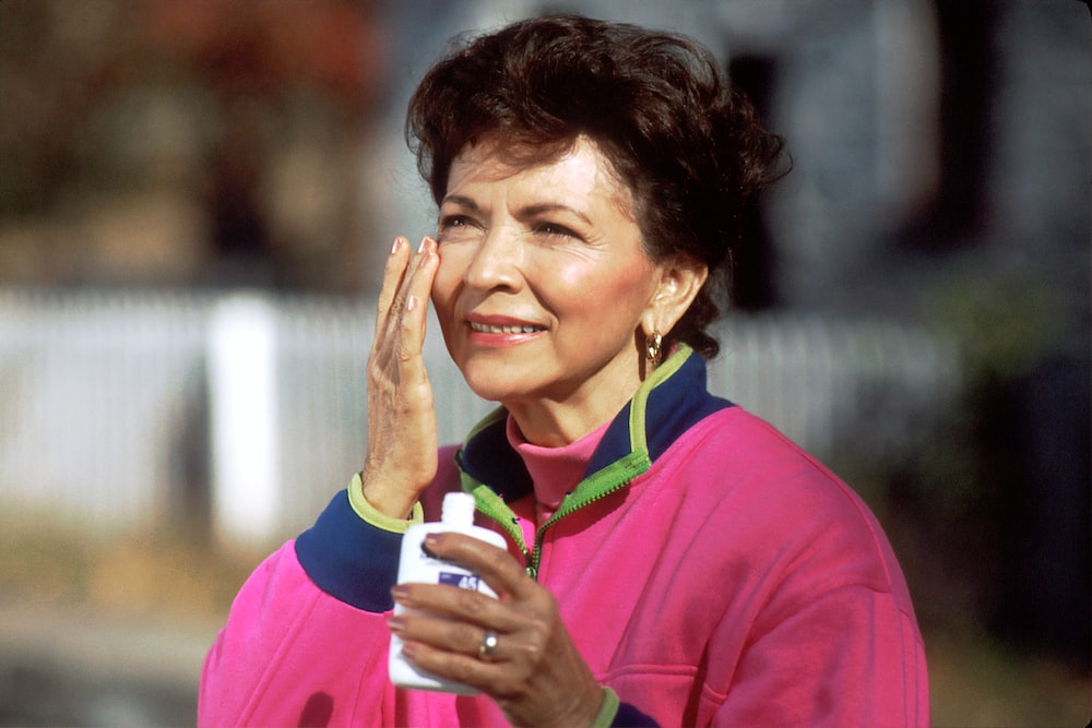 a woman applying sunscreen on her face