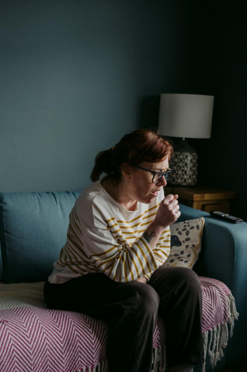 a woman coughing while sitting on a couch