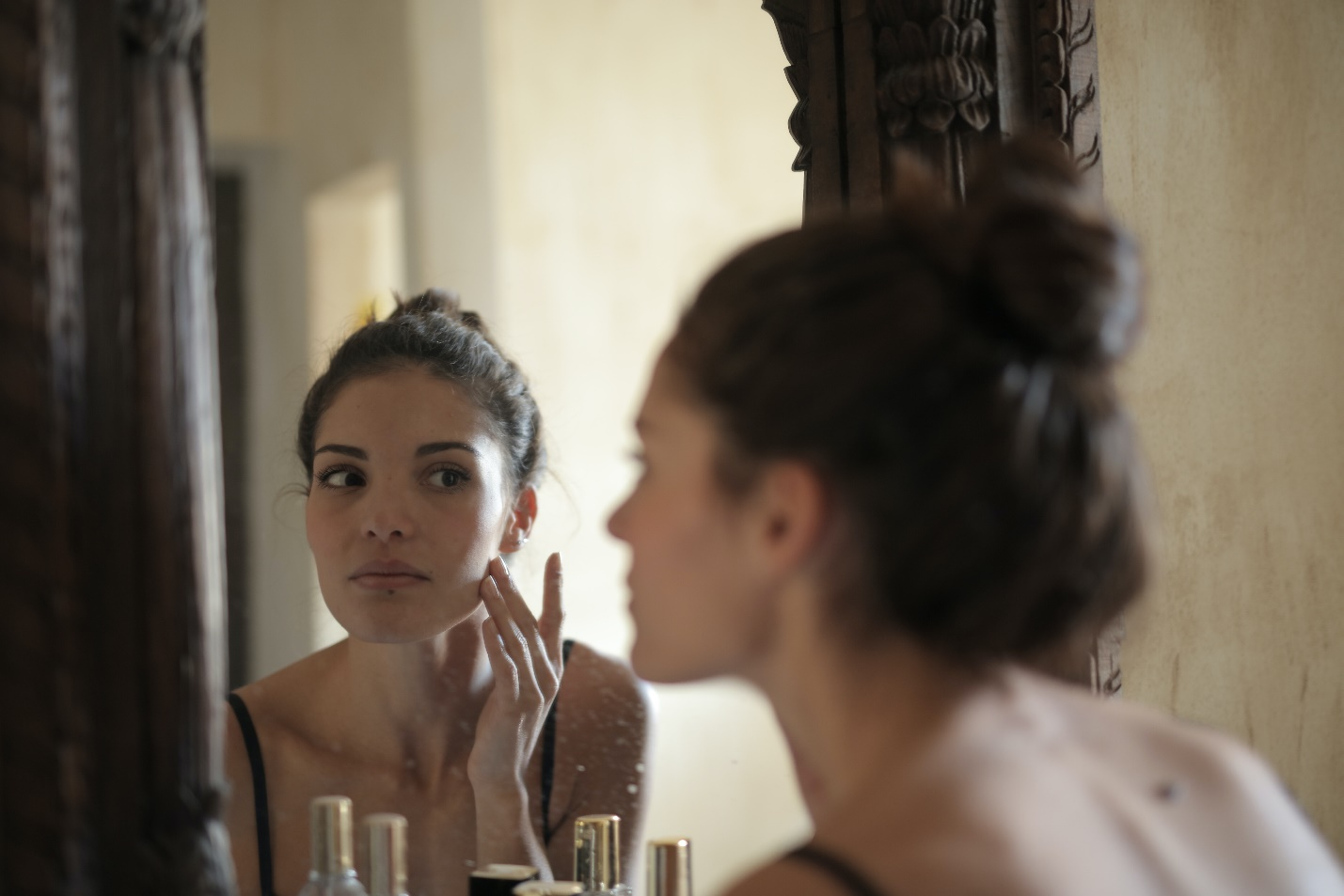 Reflection of a woman touching her face