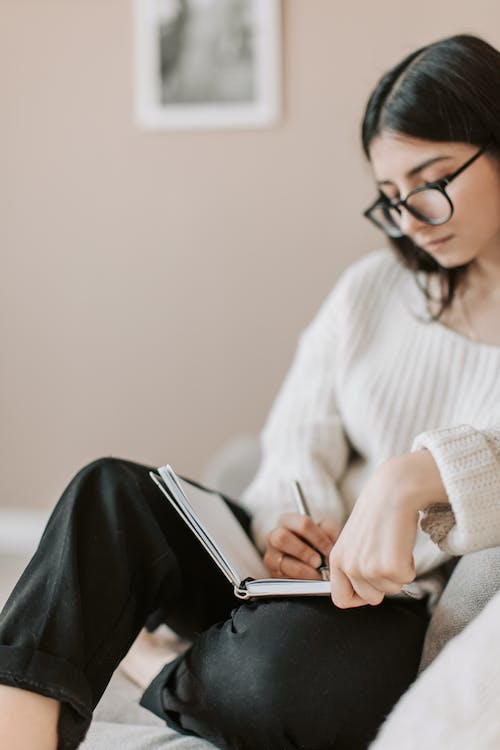 A woman is writing her medication record on a notepad